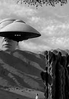 A surreal black-and-white image of a mountainous landscape with large cacti, a small human figure, and a giant face partially hidden behind a UFO hovering above the hills.